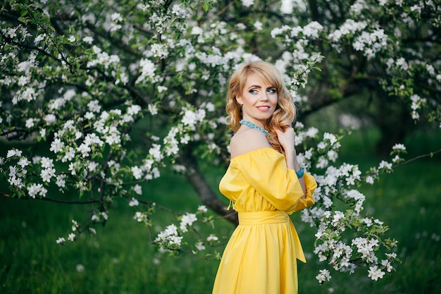 Bella ragazza in abito giallo in giardino fiorito