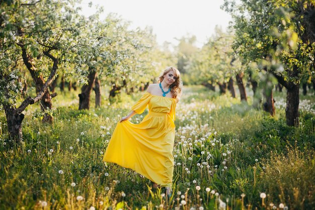 Bella ragazza in abito giallo in giardino fiorito