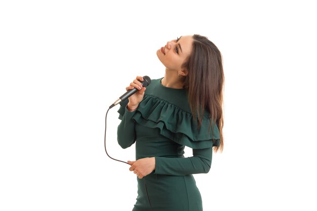 Bella ragazza in abito verde canta un karaoke isolato su sfondo bianco