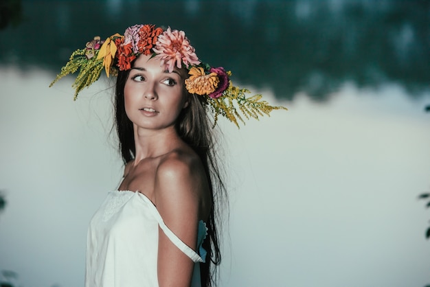 Bella ragazza in abito vintage bianco e corona di fiori