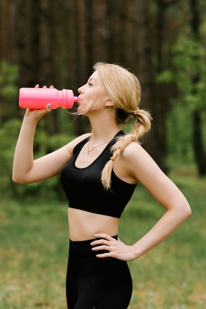 Bella ragazza in acqua potabile degli abiti sportivi