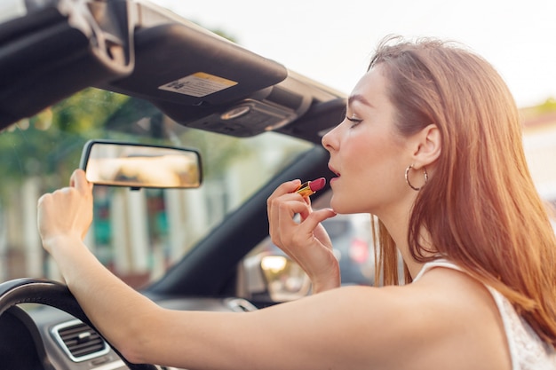 Bella ragazza in auto cabrio convertibile in una giornata di sole in una città