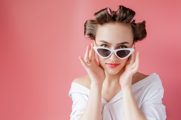 Bella ragazza in bigodini sullo spazio rosa