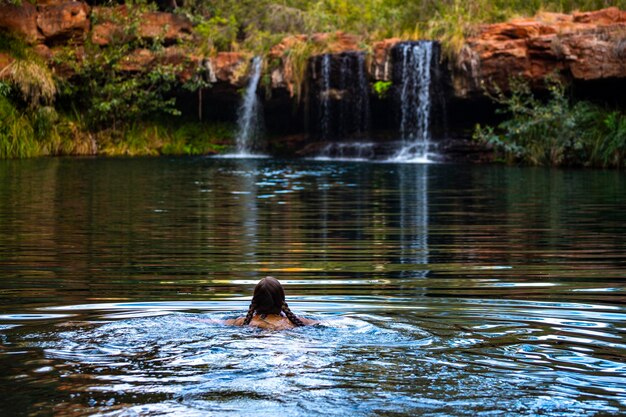 bella ragazza in bikini fa un tuffo rinfrescante in una piscina rocciosa sotto la cascata a karijini, in australia