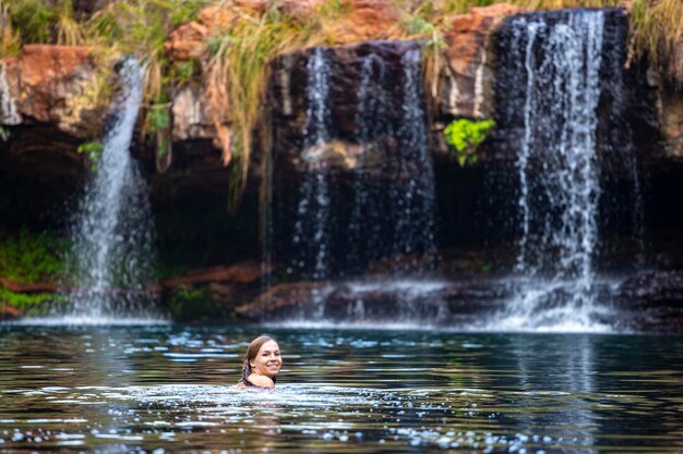 bella ragazza in bikini fa un tuffo rinfrescante in una piscina rocciosa sotto la cascata a karijini, in australia