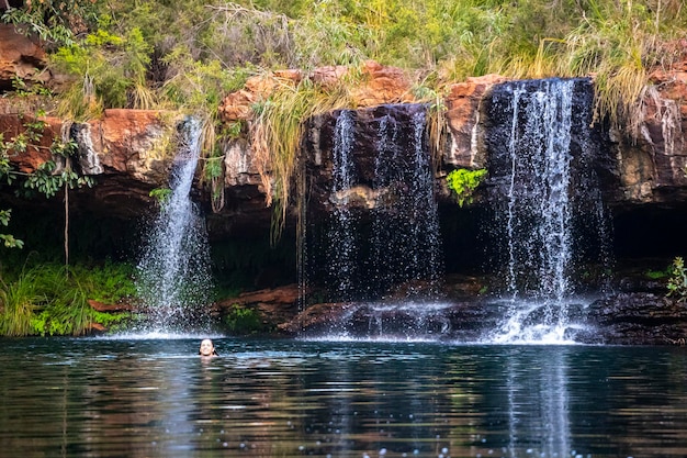 bella ragazza in bikini fa un tuffo rinfrescante in una piscina rocciosa sotto la cascata a karijini, in australia