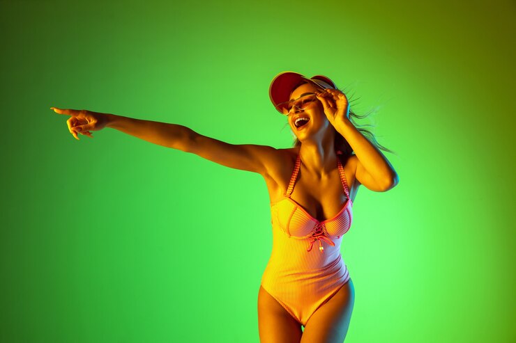 Bella ragazza in costume da bagno alla moda isolata su sfondo sfumato studio in luce al neon