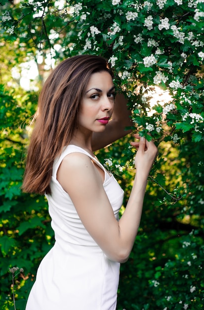 bella ragazza in estate nel parco al tramonto in un vestito sorridente