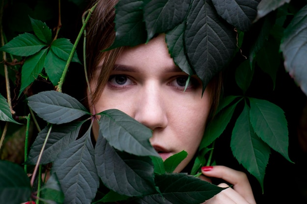Bella ragazza in foglie verdi Ritratto di donna attraente nel viso delle piante