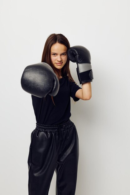 Bella ragazza in guanti da boxe uniformi sportivi neri in posa allenamento fitness