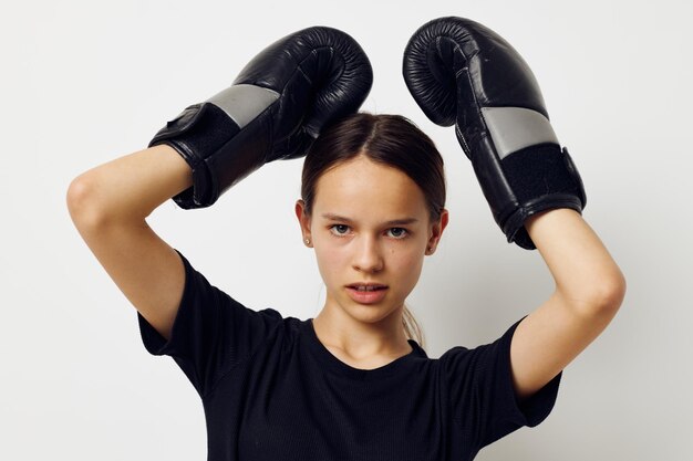 Bella ragazza in guanti da boxe uniformi sportivi neri in posa Stile di vita inalterato