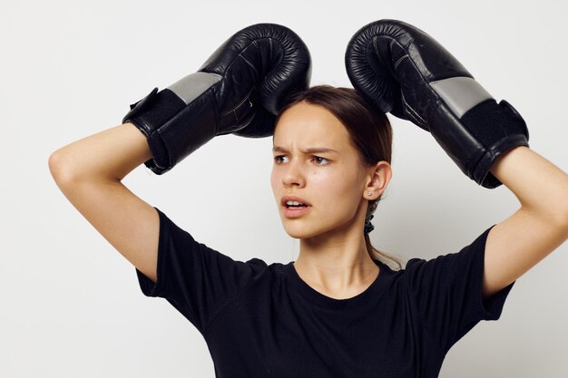 Bella ragazza in guantoni da boxe in pantaloni neri e un allenamento fitness maglietta