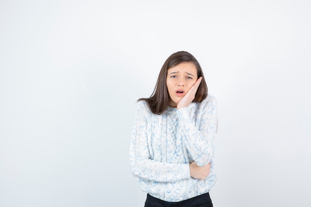 Bella ragazza in maglione lavorato a maglia in piedi e con mal di denti.