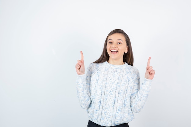 Bella ragazza in maglione lavorato a maglia in piedi e in posa.