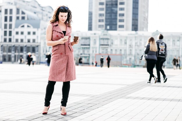 Bella ragazza in piedi con il caffè sulla strada