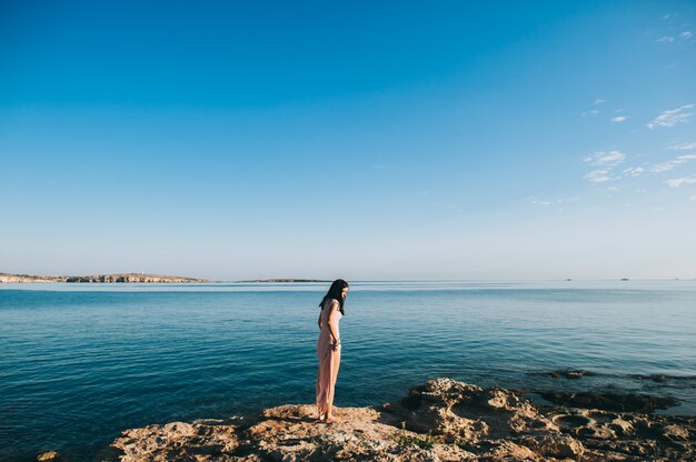 bella ragazza in piedi sulla costa rocciosa affioramenti