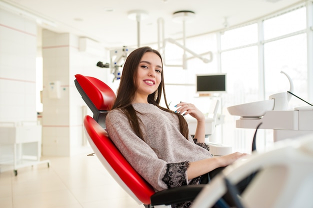 Bella ragazza in poltrona dentale rossa.