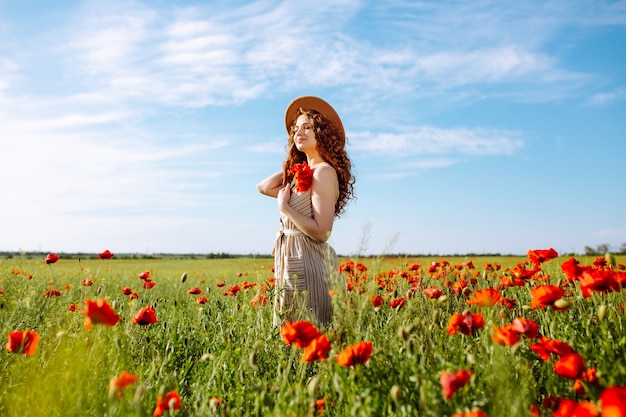 Bella ragazza in posa in un campo di papaveri