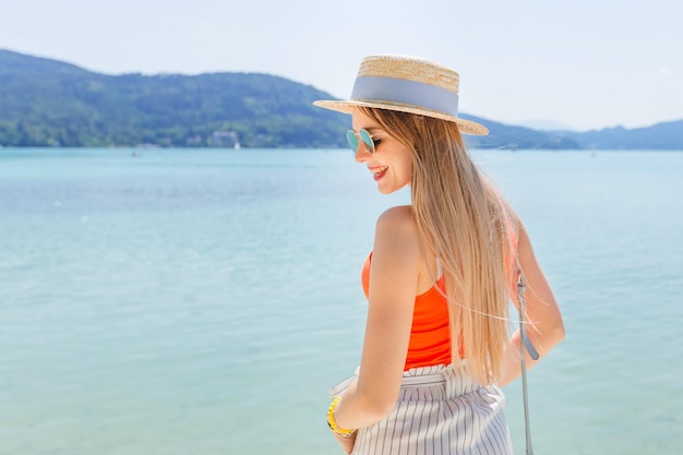 Bella ragazza in posa vicino al lago con le montagne sullo sfondo