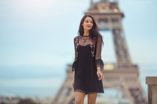 Bella ragazza in posa vicino alla Torre Eiffel