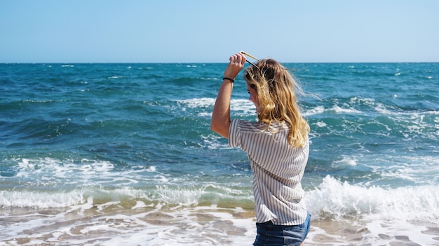 Bella ragazza in stile bohémien e abbronzata sulla spiaggia del mare alla luce del sole