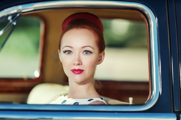 Bella ragazza in stile retrò e un'auto d'epoca