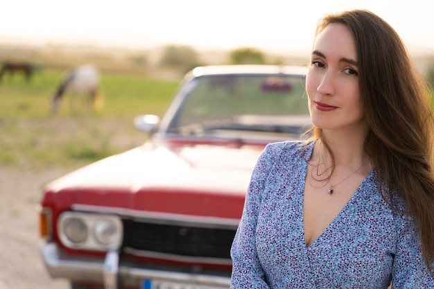 Bella ragazza in stile retrò in posa vicino a un'auto cabriolet rossa d'epoca