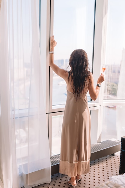 Bella ragazza in un abito lungo nella camera d'albergo