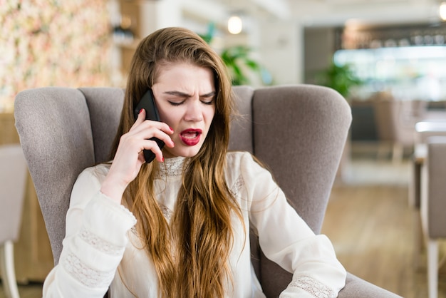 Bella ragazza in un caffè parlare su un cellulare