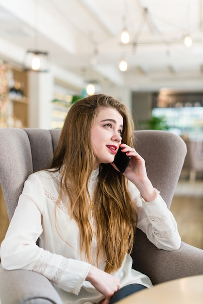 Bella ragazza in un caffè parlare su un cellulare