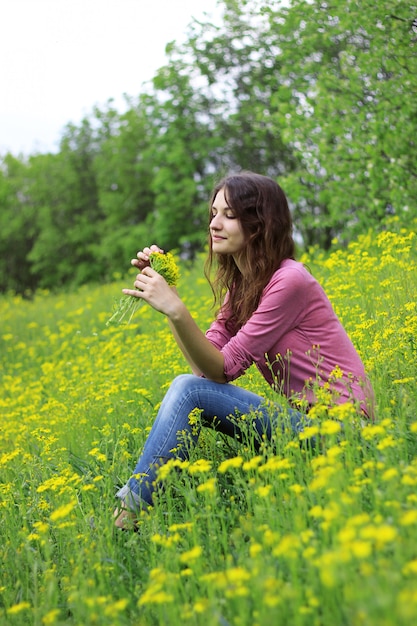 Bella ragazza in un campo di girasoli in possesso di un mazzo di fiori.