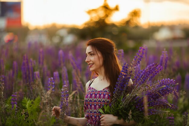 Bella ragazza in un campo di lupino. Ragazza che tiene un mazzo di lupini