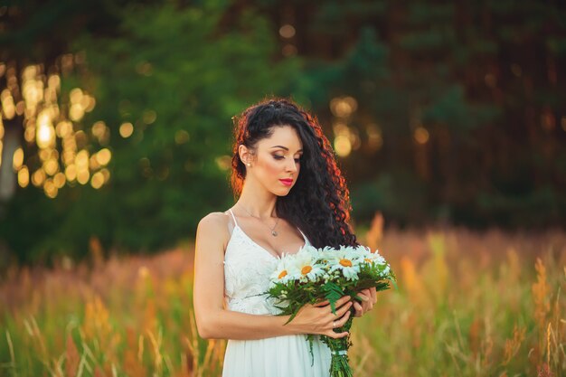 Bella ragazza in un campo in un vestito bianco