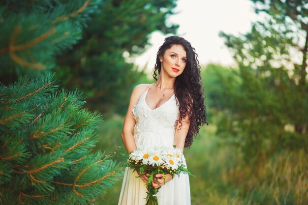 Bella ragazza in un campo in un vestito bianco