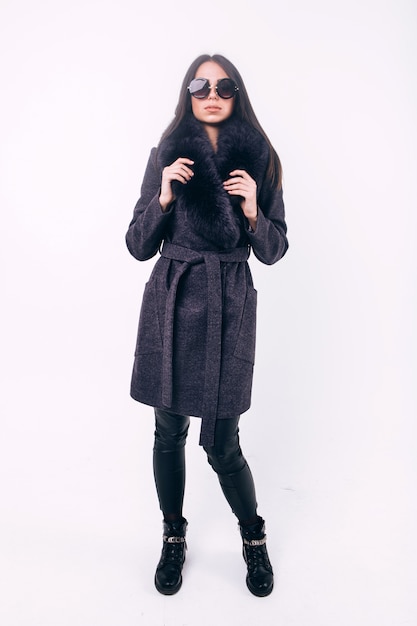 Bella ragazza in un cappotto caldo con cappuccio di pelliccia, fotografia in studio di abbigliamento invernale