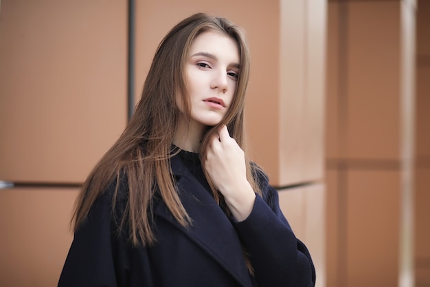 Bella ragazza in un cappotto nel centro di affari del nuvoloso