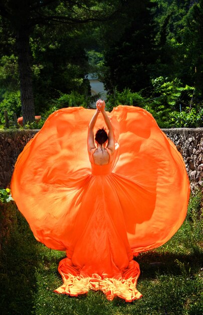 Bella ragazza in un incredibile vestito arancione svolazzante Concetto di farfalla