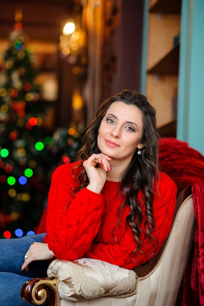 Bella ragazza in un maglione rosso vicino all'albero di Natale.