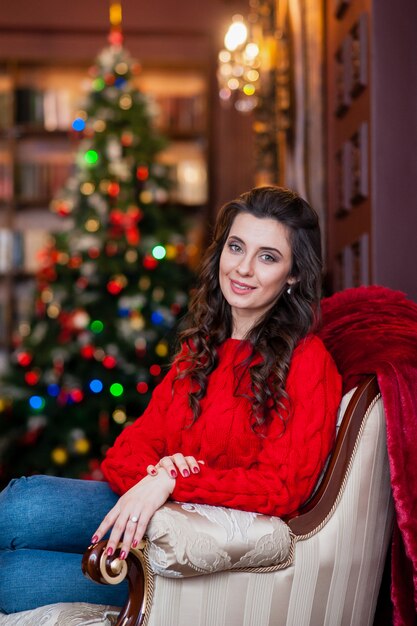 Bella ragazza in un maglione rosso vicino all&#39;albero di Natale.