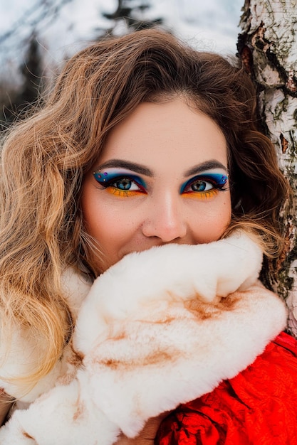 Bella ragazza in un mantello rosso nella foresta d'inverno