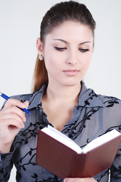 Bella ragazza in un tailleur grigio con un diario e una penna per scrivere in mano