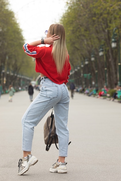 Bella ragazza in un top rosso jeans a vita alta che cammina per strada