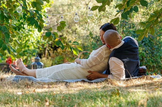 Bella ragazza in un vestito bianco e un ragazzo giacciono in una radura un picnic