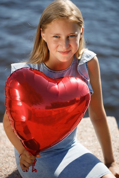 Bella ragazza in un vestito blu con un palloncino a forma di cuore