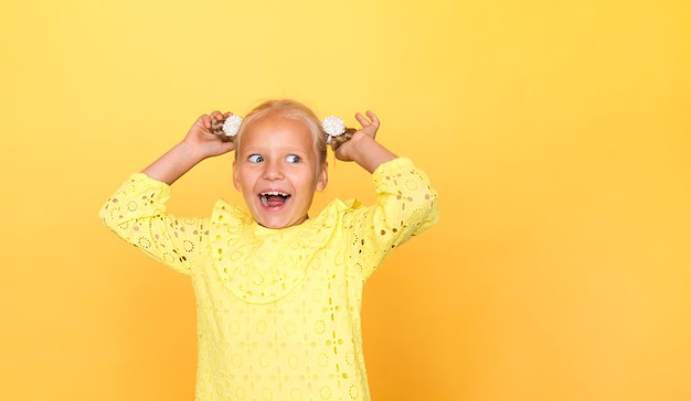 Bella ragazza in un vestito giallo su uno sfondo giallo solido. Bionda con i capelli lunghi. Emozioni.