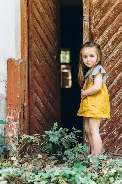 bella ragazza in un vestito giallo vicino a una porta di legno