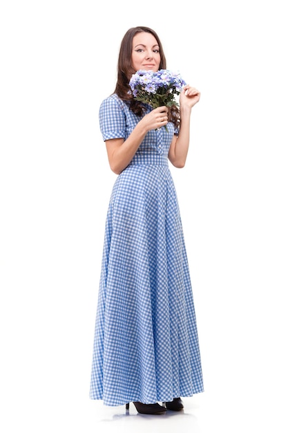 Bella ragazza in un vestito in una gabbia blu con fiori di crisantemi in mani su sfondo bianco
