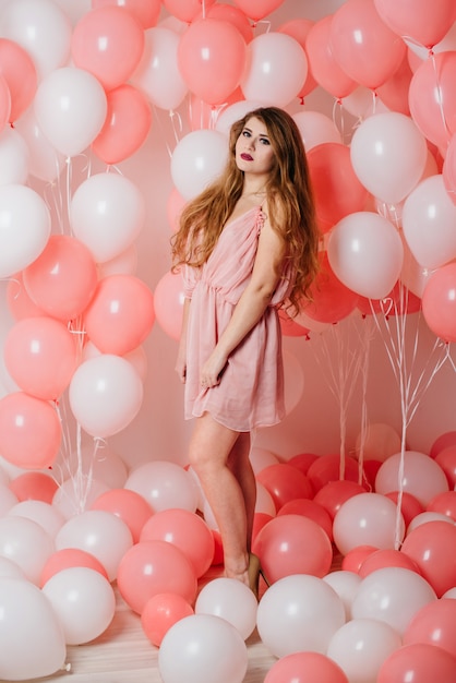 Bella ragazza in un vestito tra un sacco di palline rosa.