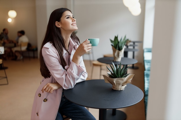 Bella ragazza in una caffetteria con una tazza di caffè