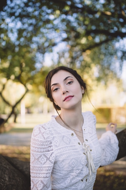 Bella ragazza in una camicetta di pizzo bianco in un parco in autunno